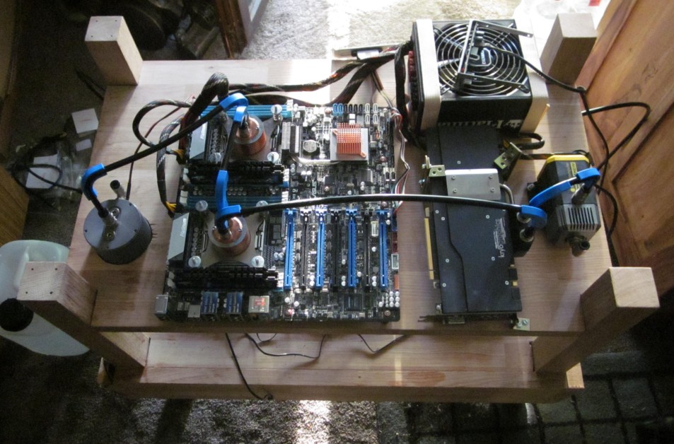 Picture of a dual CPU motherboard with water coolers mounted on a table-like wood construction